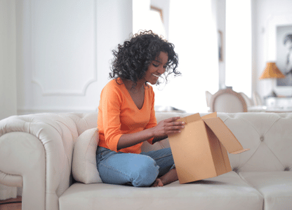 A woman on the couch opens a package