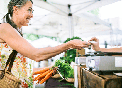 A woman buying carrots at the farmers market