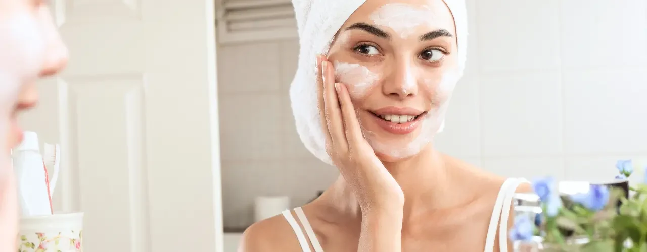 A woman doing a skin care routine in front of a mirror